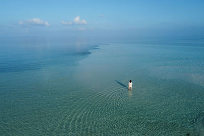 Woman walking through the ocean on an island in the maldives