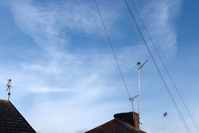 Low angle view of power cables against sky