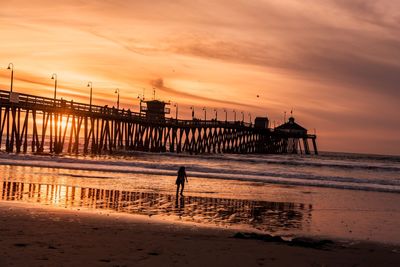 Silhouette man standing on beach against sky during sunset