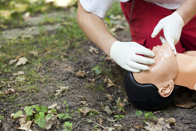 Low section of man practicing cpr on dummy at field