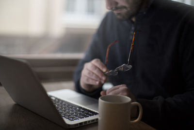 Midsection of man holding coffee cup