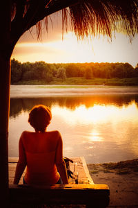 Silhouette of people sitting on bench at sunset