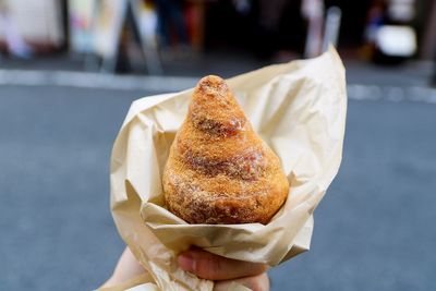 Close-up of human hand holding snack in city