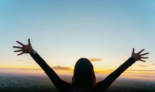 Cropped image of hand against clear sky during sunset