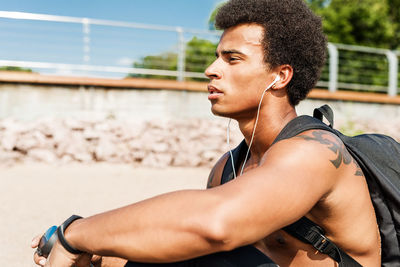 Side view of young man looking at camera