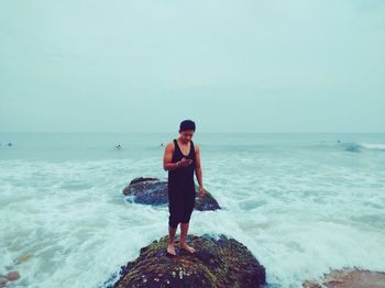 Full length of woman standing on beach against sky