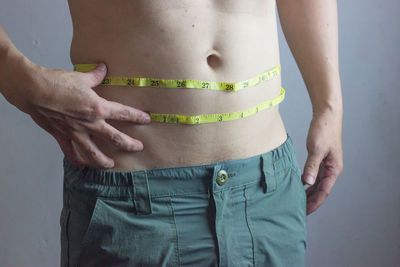 Midsection of man standing against gray background
