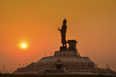 Low angle view of buddha statue against sky during sunset