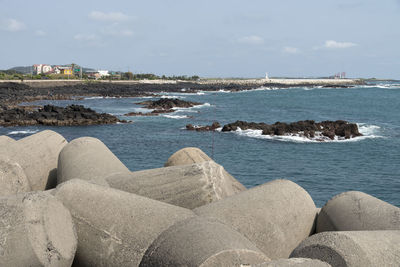 Tetra pods at beach against sky