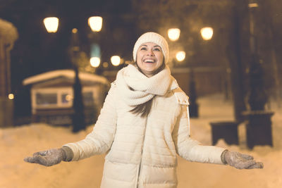 Woman standing on snow covered street at night