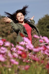 Portrait of smiling woman with pink flower on field