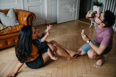 Rear view of friends sitting on floor at home