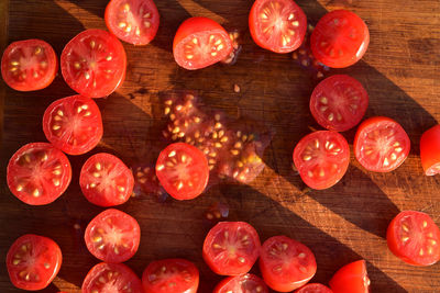 Above view of grape tomatoes cut into halves on wood cutting board