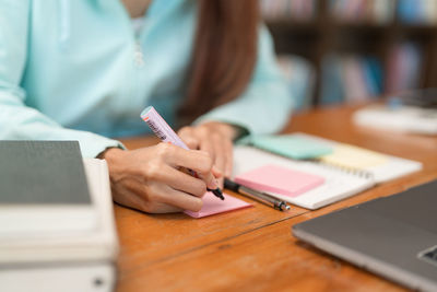 College education concept, teenage girl is writing vocabulary on sticky note while study tutorial.