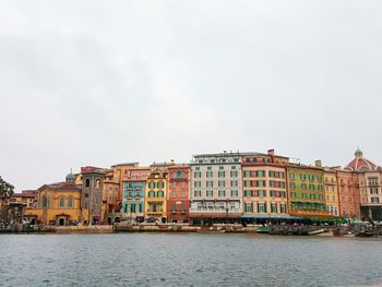 Buildings at waterfront against cloudy sky