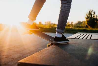 Low section of woman standing on floor against sky during sunset