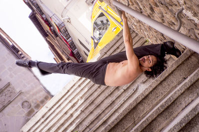 Portrait of shirtless mature man balancing upside down on steps in city