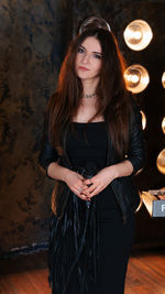 Portrait of young woman standing against wall