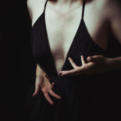 Midsection of woman standing against black background
