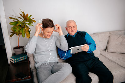 Happy man with headphones sitting on sofa at home