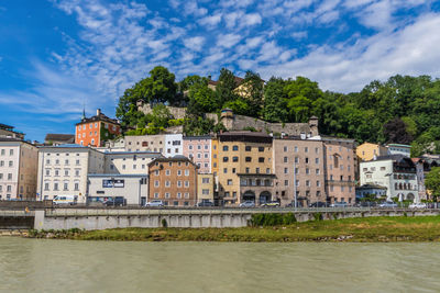 Buildings by river against sky