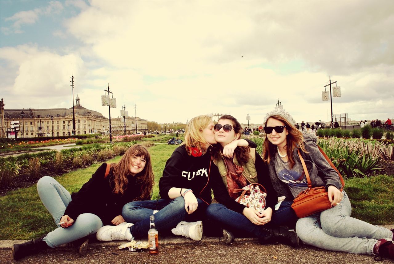 lifestyles, leisure activity, casual clothing, person, sky, young adult, young women, cloud - sky, full length, sitting, happiness, smiling, childhood, grass, looking at camera, enjoyment, togetherness