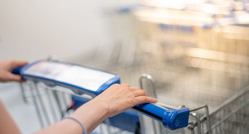 Female hand pushing shopping trolleys in supermarket walking through the aisle