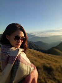 Side view portrait of woman wearing sunglasses on mountain against clear sky