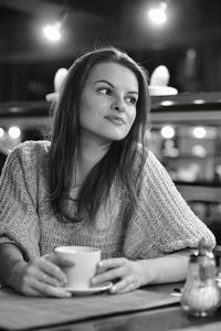 Thoughtful woman having coffee at table in restaurant