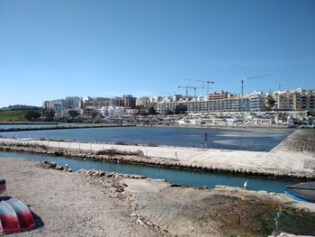 City at waterfront against blue sky