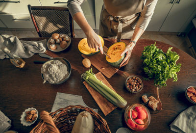 Hands of athletic woman cutting pumpkin with a knife to prepare in the kitchen at home