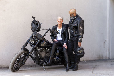 Cool mature biker couple in leather clothes posing with motorcycle