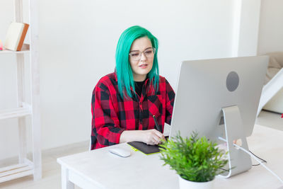 Young woman using phone while sitting on table