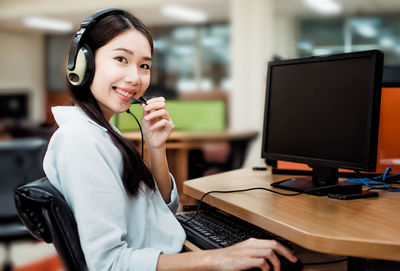 Smiling young woman using mobile phone at table