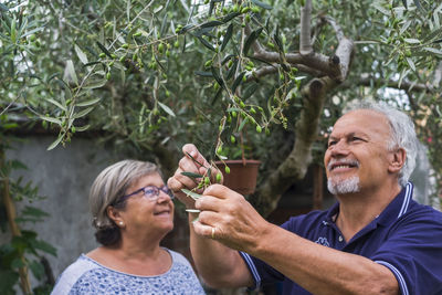 Man and woman standing by trees in yard