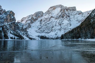 Scenic view of frozen lake by snowcapped mountains against sky