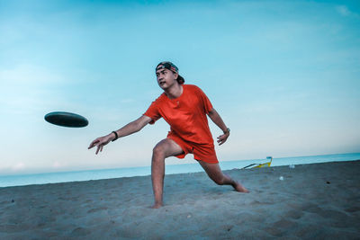 Full length of young man on beach against sky