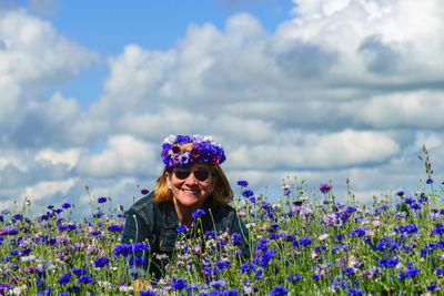 A woman in the middle of a colorful field of cornflowers is happy about summer