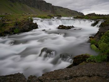 Scenic view of waterfall against sky