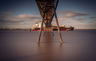 Pier over sea by boat against sky