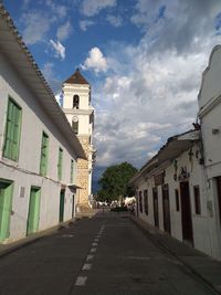 Empty road amidst buildings against sky