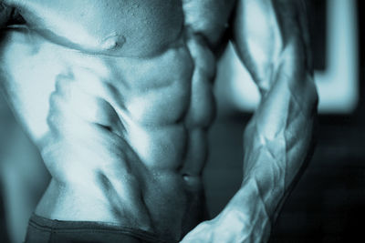 Midsection of shirtless muscular man in gym