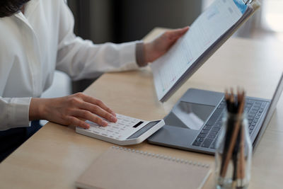 Midsection of woman using laptop on table