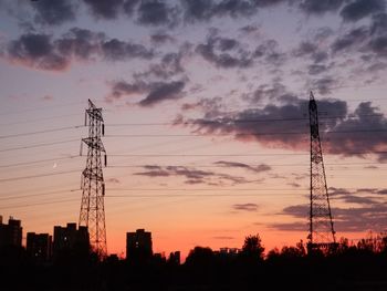 Low angle view of silhouette electricity pylon against sky during sunset