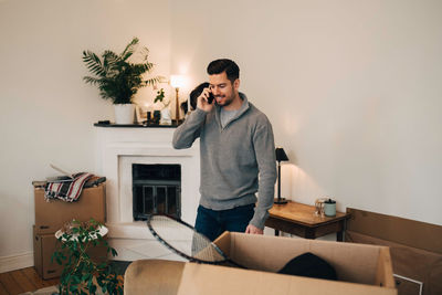 Smiling man talking on mobile phone while standing in living room