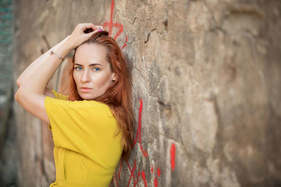 Portrait of woman standing by wall