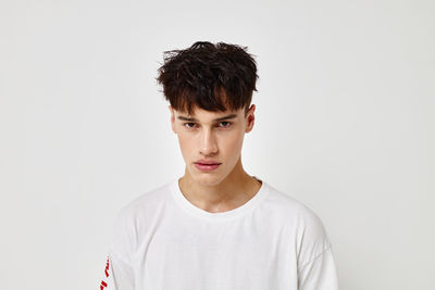 Portrait of young man standing against white background