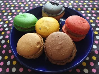 High angle view of colorful macaroons in plate on tablecloth