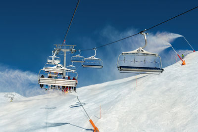Ski lift over snowcapped mountain against sky