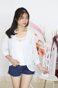 Portrait of young woman standing against wall